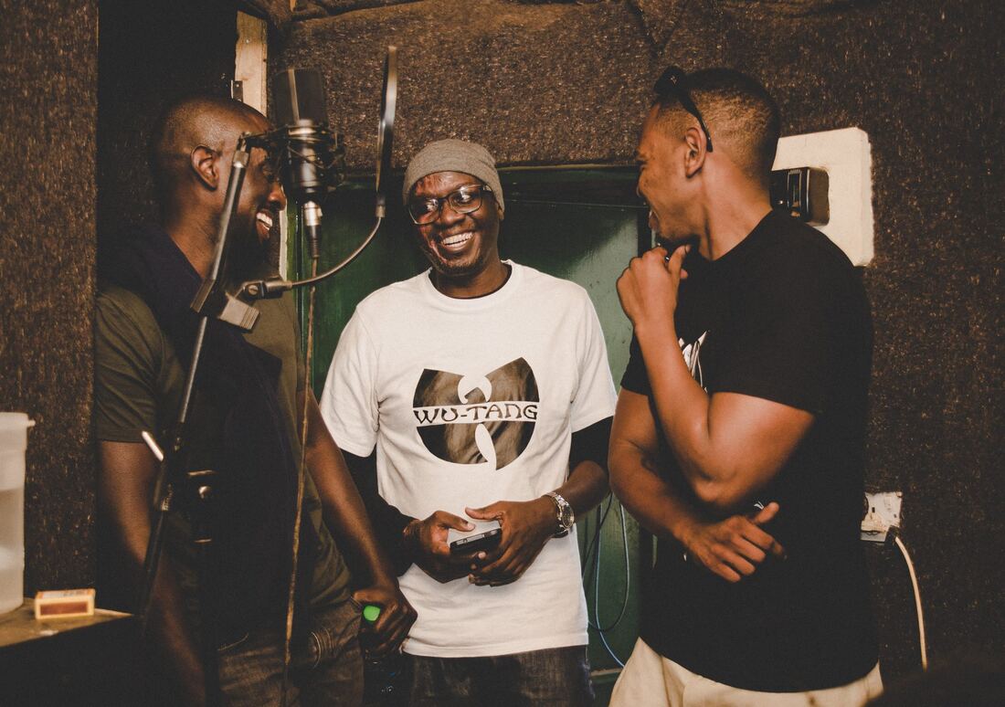 Solodified laughing with collaborators in the vocal booth doorway