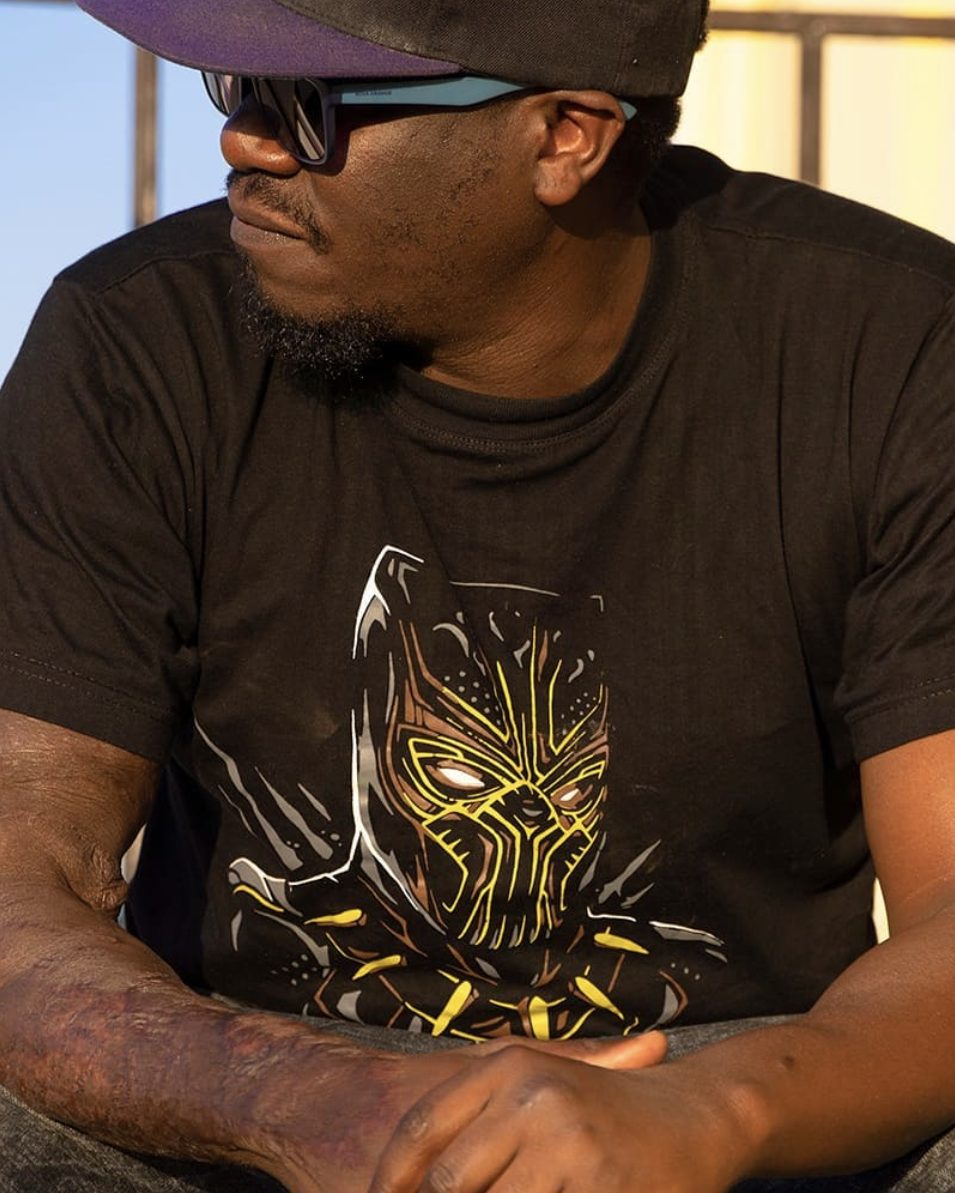 Solodified in a gold Black Panther tee in golden-hour light